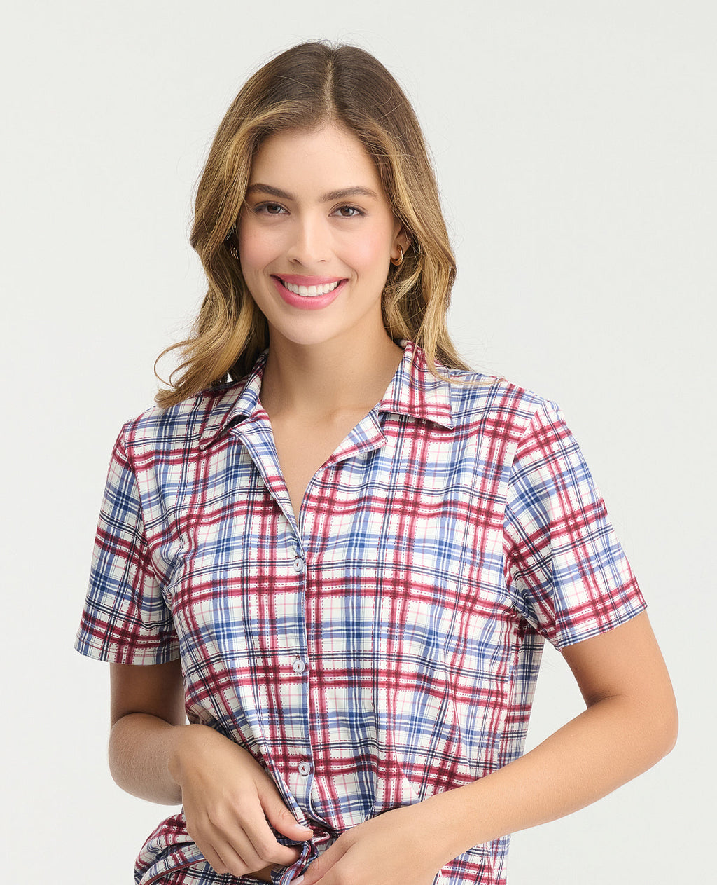 Mujer usando camisa de pijama manga corta a cuadros rojos y azules con cuello clásico y botones frontales.