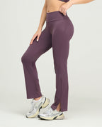 Pantalón deportivo tipo leggings color morado, silueta ajustada con bota recta y abertura lateral en el tobillo.