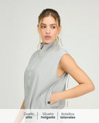 Chaleco deportivo gris para mujer con cuello alto, cremallera frontal y bolsillos laterales de silueta holgada.