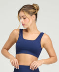 Modelo usando top deportivo azul con escote cuadrado, cargaderas anchas y tecnología seamless sin costuras.