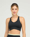 Top deportivo negro ajustado con cargaderas anchas y base estructurada cruzada frontal sobre fondo gris claro.