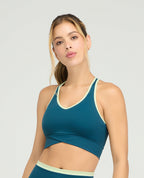 Top deportivo azul petróleo para mujer de silueta ajustada con cargaderas anchas y base cruzada de soporte.