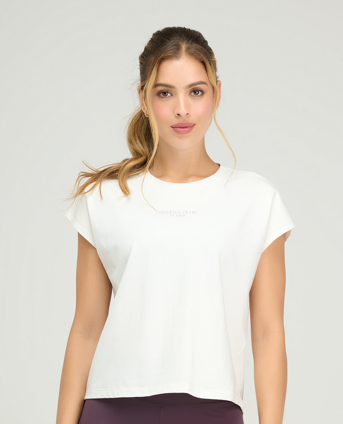 Camiseta deportiva blanca holgada para mujer con manga rodada y detalle de texto en el pecho de St. Even.