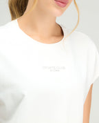Primer plano de camiseta deportiva blanca St.Even para mujer con estampado Sports Club en pecho y cuello redondo.