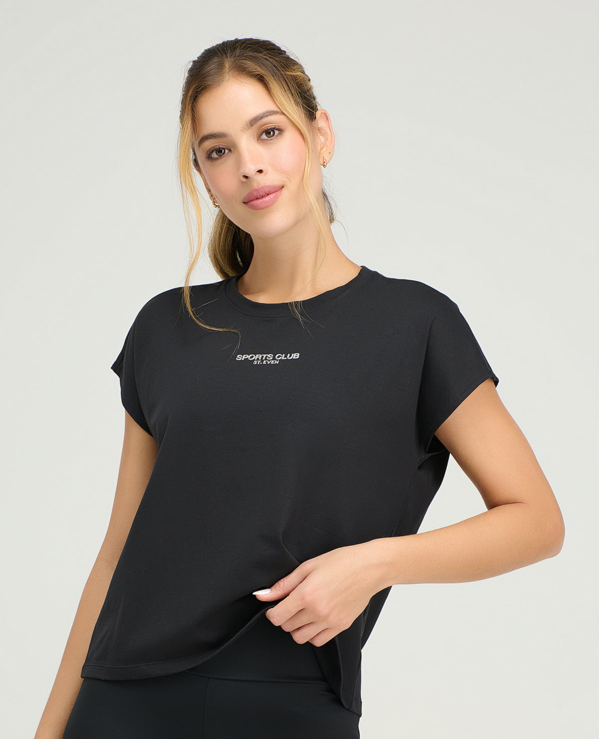 Mujer usando camiseta deportiva negra holgada con cuello redondo y manga rodada St. Even para entrenamiento.