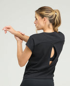 Vista posterior de camiseta deportiva negra para mujer con abertura en espalda, silueta holgada y manga rodada.