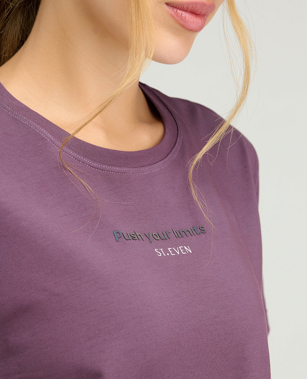 Primer plano de camiseta deportiva morada con cuello redondo y estampado reflectivo de la marca St. Even.
