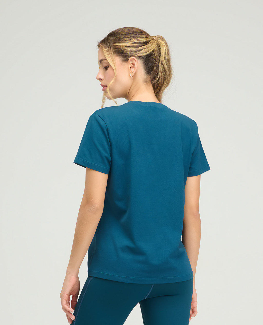 Vista posterior de camiseta deportiva azul para mujer, silueta holgada, cuello redondo y manga corta de tela suave.