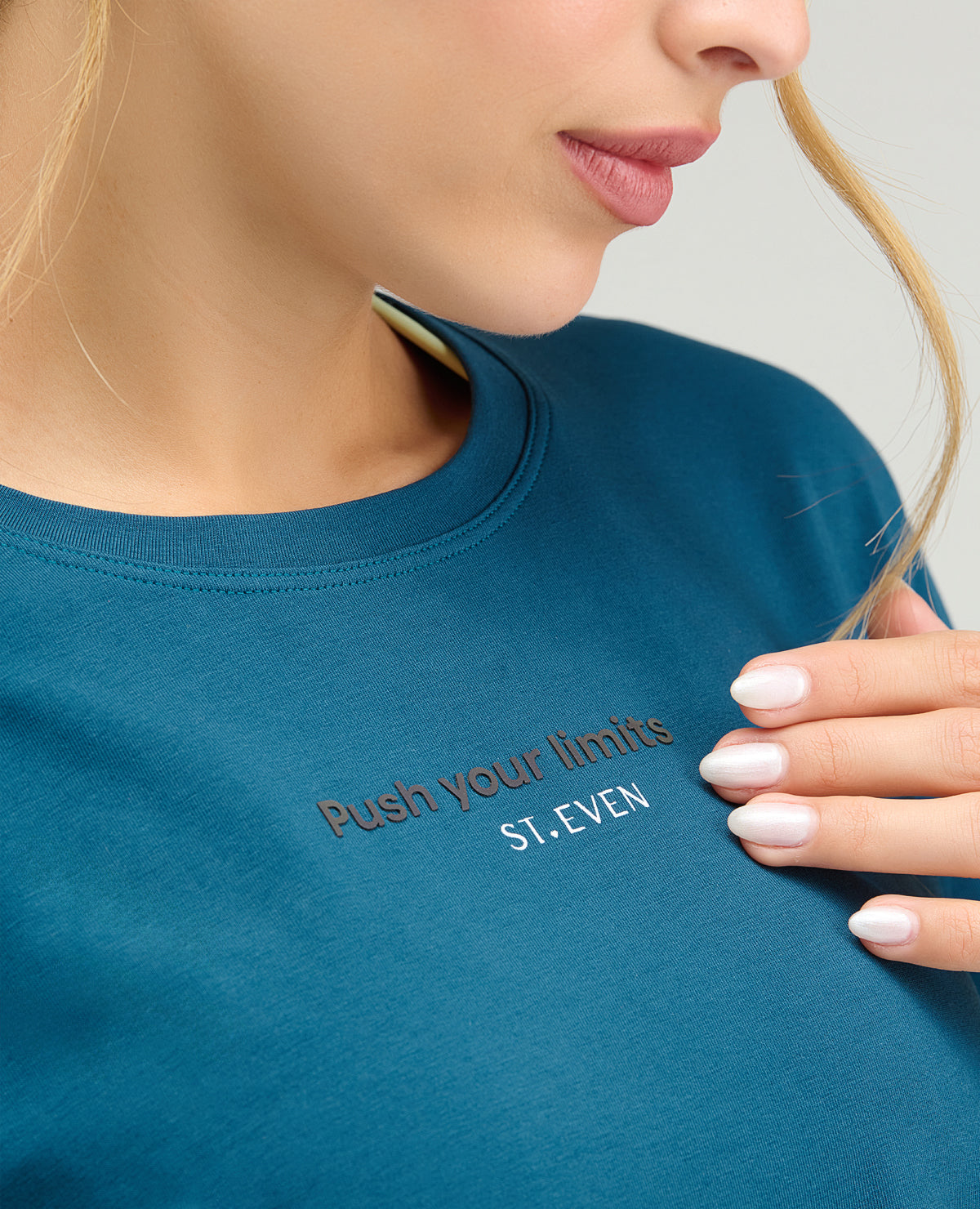 Detalle de camiseta deportiva azul con cuello redondo y estampado reflectivo Push your limits de St. Even.