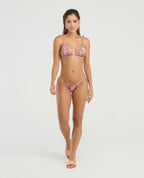 Modelo luciendo panty de baño tiro bajo con ajuste lateral graduable y estampado multicolor para moda playa.