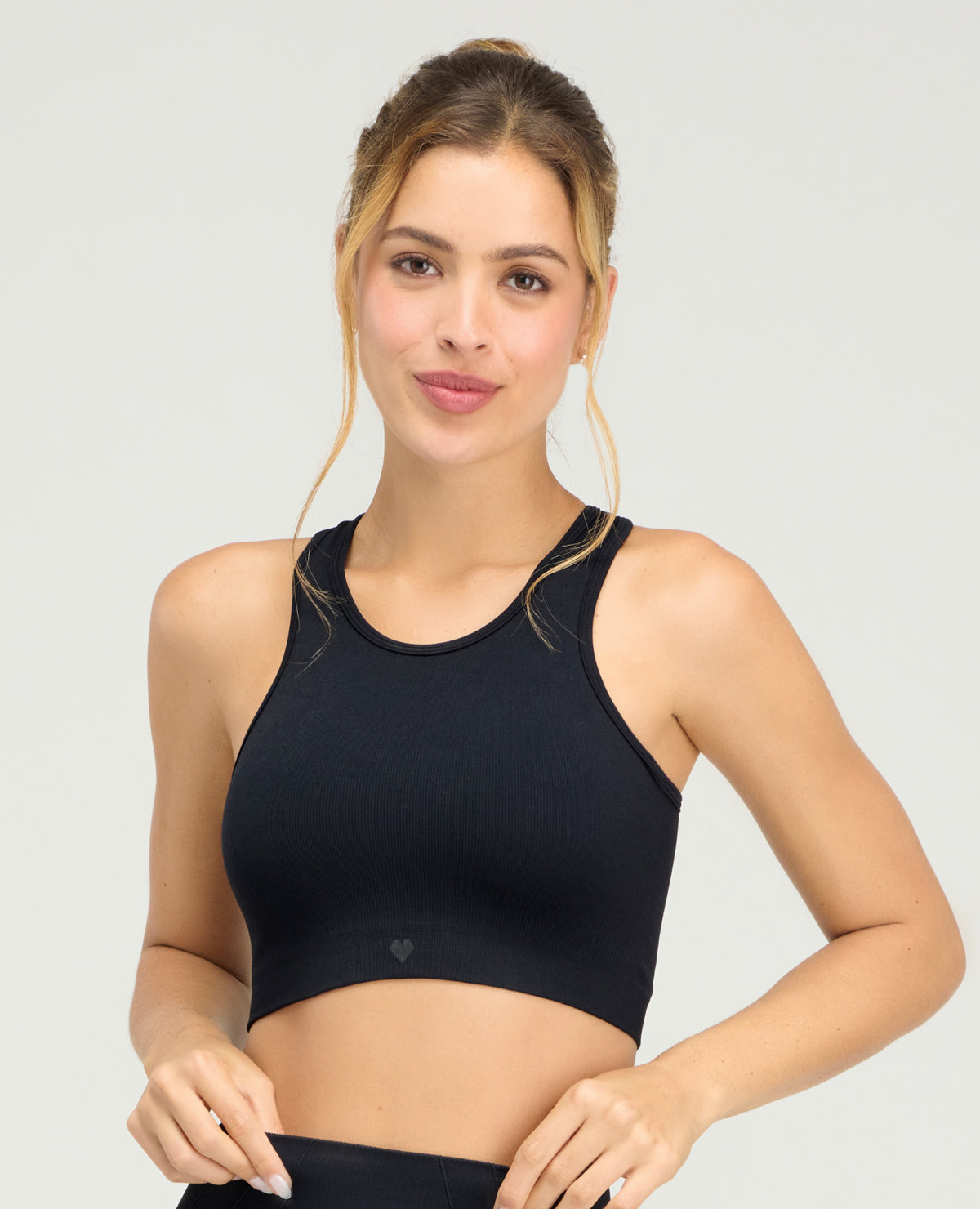 Mujer usando top deportivo negro sin costuras St. Even, tecnología seamless con cuello redondo y espalda atlética.