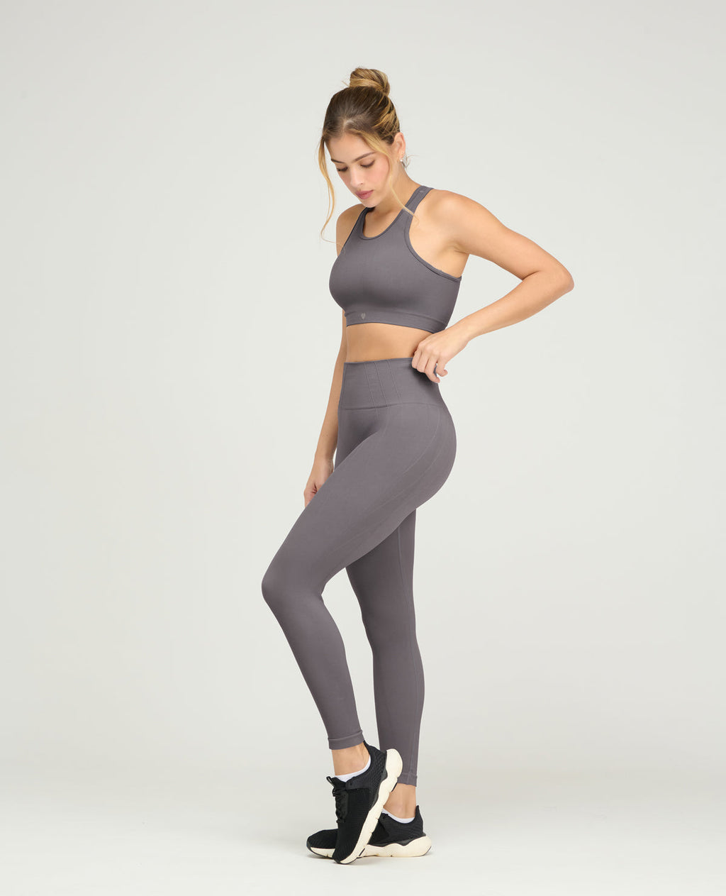 Modelo usando top deportivo gris sin costuras y leggings a juego, ideal para yoga o entrenamiento fitness en Colombia.