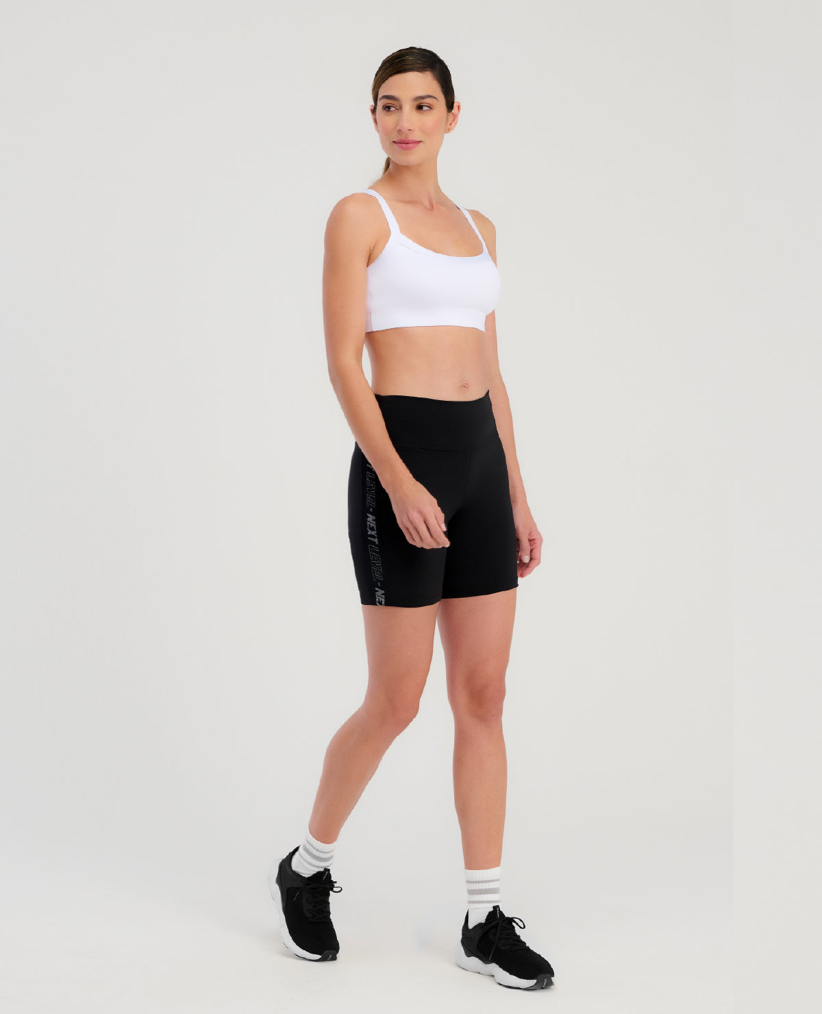 Mujer usando Top Deportivo St Even blanco básico, Ref 63766, de doble tela sin transparencias y shorts negros.