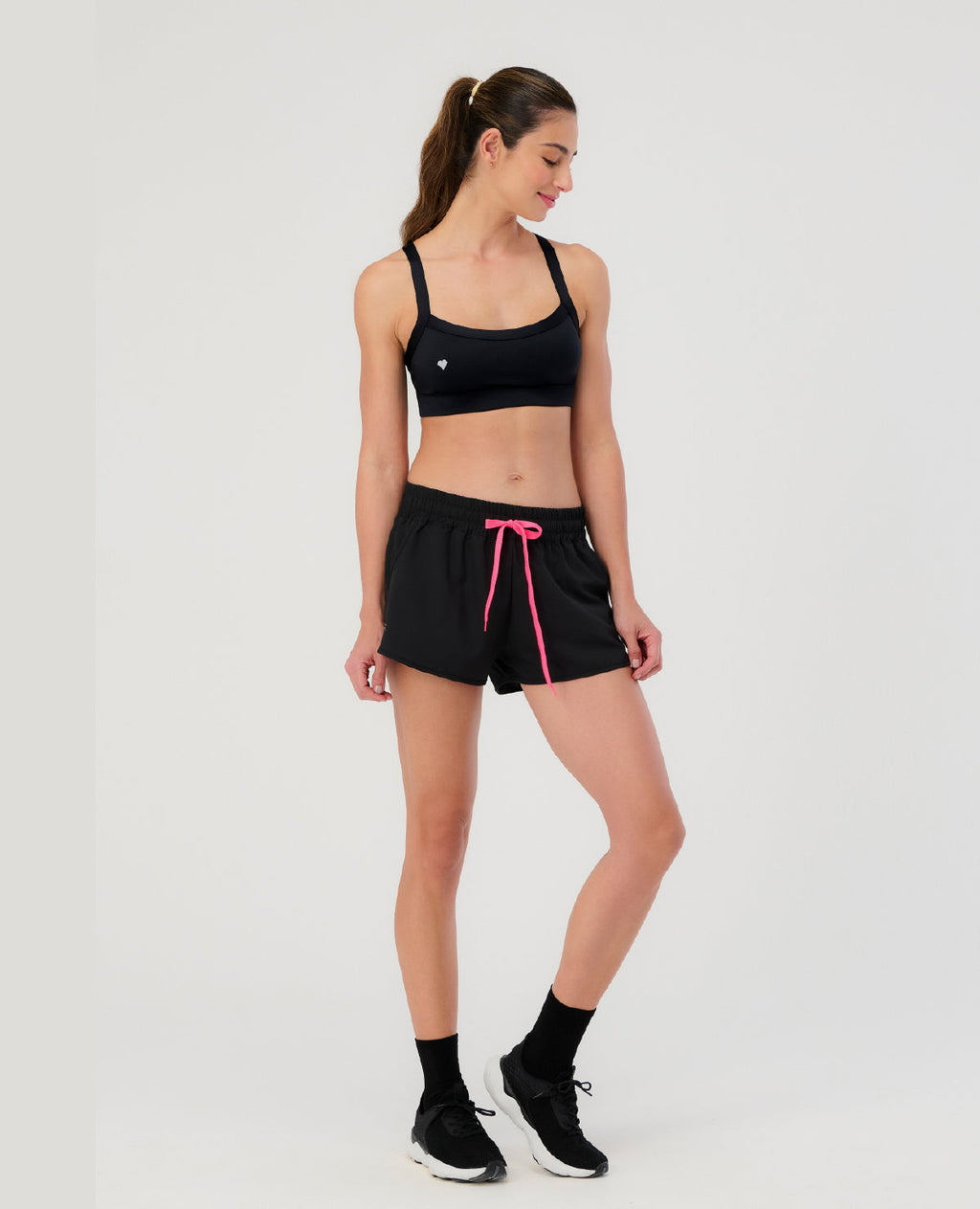 Mujer usando top deportivo negro St Even de tela inteligente y shorts para gimnasio. Ropa deportiva colombiana.